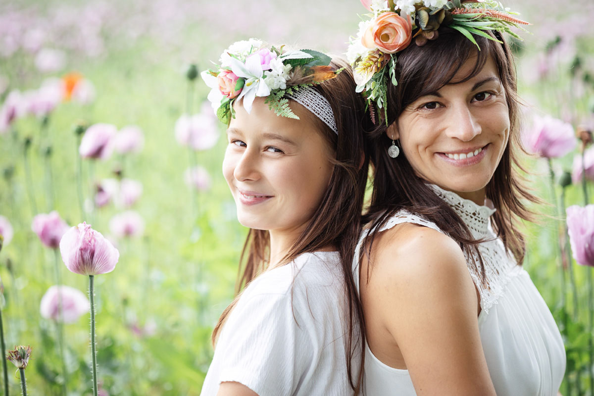 Mutter und Tochter Rücken an Rücken Mutter und Tochter Rücken an Rücken im Mohnblumenfeld